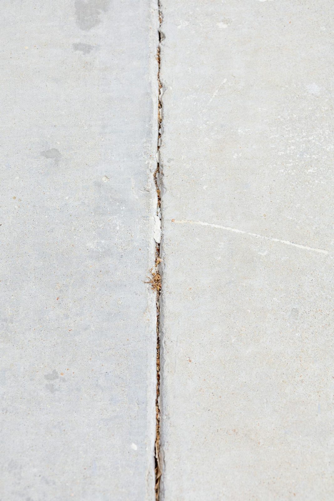 Close-up of a cracked sidewalk seam between concrete panels — the kind of trip hazard polyjacking eliminates